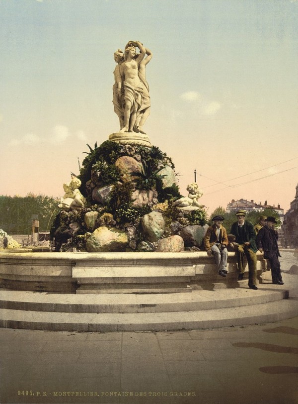 Old photo of four men sitting next to the fountain and statue of the Three Graces in Montpellier.